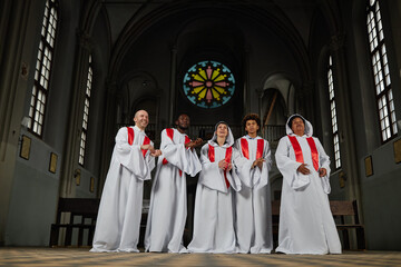 Wall Mural - Group of people in white costumes singing in church choir they standing in old church and clapping hands during performance