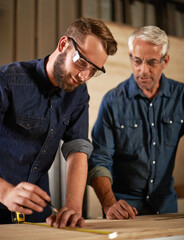 Canvas Print - Wood, learning and carpentry apprentice with mentor in designer furniture manufacturing workshop. Mentorship, senior carpenter and young man, measuring tape and focus on teaching sustainable business