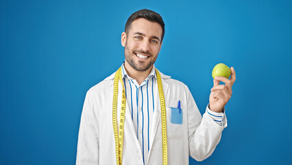 Poster - Young hispanic man dietician smiling confident holding apple over isolated blue background