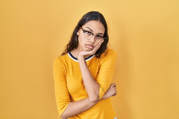 Sticker - Young brazilian woman wearing glasses over yellow background thinking looking tired and bored with depression problems with crossed arms.