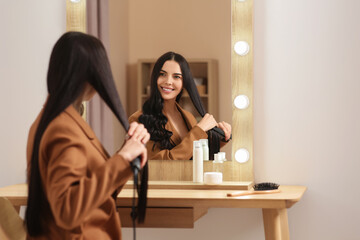 Sticker - Beautiful happy woman using hair iron near mirror in room