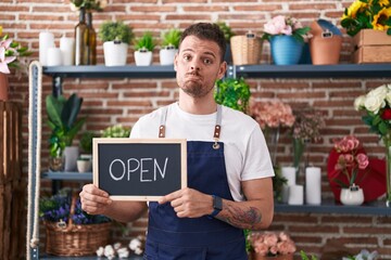 Canvas Print - Young hispanic man working at florist holding open sign depressed and worry for distress, crying angry and afraid. sad expression.