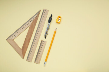 Wall Mural - Different rulers, pencil, and compass on yellow background. Space for text