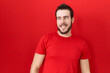 © Krakenimages.com - Young hispanic man wearing casual red t shirt looking away to side with smile on face, natural expression. laughing confident.