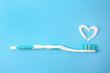 Heart made with toothpaste and brush on light blue background, top view