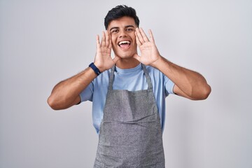 Sticker - Hispanic young man wearing apron over white background smiling cheerful playing peek a boo with hands showing face. surprised and exited