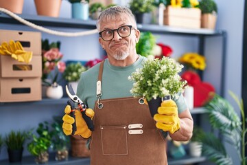 Sticker - Hispanic man with grey hair working at florist shop smiling looking to the side and staring away thinking.