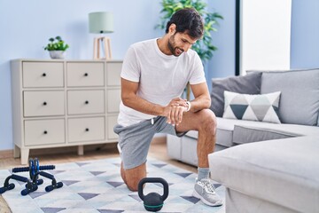 Sticker - Young hispanic man sporty using stopwatch at home