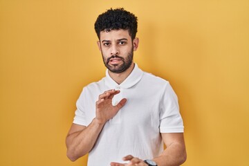 Wall Mural - Arab man standing over yellow background disgusted expression, displeased and fearful doing disgust face because aversion reaction.