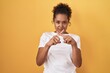 © Krakenimages.com - Young hispanic woman with curly hair standing over yellow background rejection expression crossing fingers doing negative sign