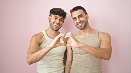 Poster - Two men couple hugging each other doing heart gesture over isolated pink background