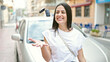 © Krakenimages.com - Young beautiful hispanic woman holding key standing by car at street