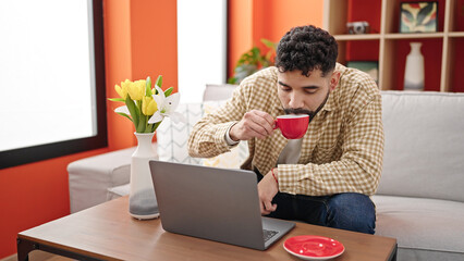 Sticker - Young hispanic man using laptop drinking coffee at h