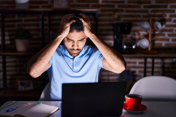 Canvas Print - Hispanic man with beard using laptop at night suffering from headache desperate and stressed because pain and migraine. hands on head.