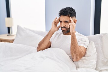 Sticker - Young hispanic man suffering for headache sitting on bed at bedroom