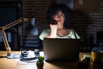 Canvas Print - Young brunette woman with curly hair working at the office at night showing middle finger, impolite and rude fuck off expression