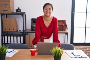 Wall Mural - Young chinese woman business worker smiling confident standing by desk at office