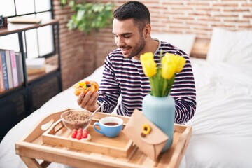 Sticker - Young hispanic man having gift breakfast sitting on bed at bedroom