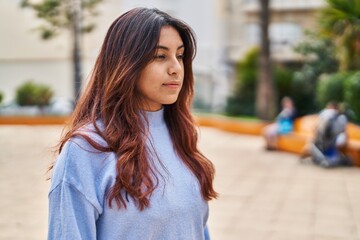 Poster - Young hispanic woman with relaxed expression standing at park