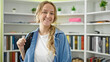 © Krakenimages.com - Young blonde woman student wearing backpack smiling at library university