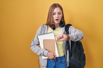 Canvas Print - Young caucasian woman wearing student backpack and holding books looking at the watch time worried, afraid of getting late