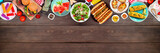 Fototapeta Kawa jest smaczna - Summer BBQ food top border. Hamburgers, hot dogs, potatoes, corn and cold treats. Overhead view over a dark wood banner background. Copy space.