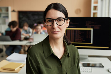 young woman as female teacher in programming class for children looking at camera