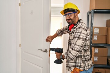 Wall Mural - Young hispanic man worker smiling confident repairing door at home