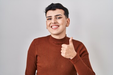 Canvas Print - Non binary person wearing make up standing over isolated background smiling happy and positive, thumb up doing excellent and approval sign