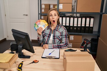 Poster - Young blonde doctor woman working at small business ecommerce holding swiss francs scared and amazed with open mouth for surprise, disbelief face