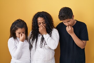 Sticker - Family of mother, daughter and son standing over yellow background tired rubbing nose and eyes feeling fatigue and headache. stress and frustration concept.