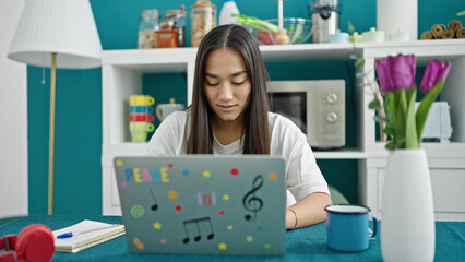 Wall Mural - Young beautiful hispanic woman using laptop sitting on table at dinning room