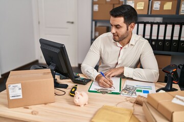 Wall Mural - Young hispanic man e-commerce business worker writing on document at office