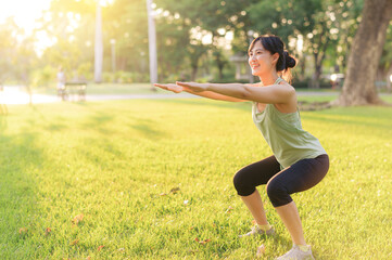 Female jogger. Fit young Asian woman with green sportswear squatting in park before running and enjoying a healthy outdoor. Fitness runner girl in public park. Wellness being concept