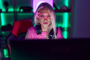 Wall Mural - Young blonde woman streamer using computer and virtual reality glasses at gaming room