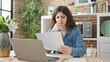 © Krakenimages.com - Young beautiful hispanic woman reading document with serious expression at dinning room