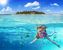 Split Image With A Tropical Island And Underwater Life With A Girl Snorkeling In The Ocean Of The Maldives With Colorful Fish