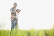 © Serhii - Portrait of senior farmer standing in wheat field examining crop during the day.