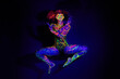 © L De Bruin/peopleimages.com - Body paint, dance and portrait of a woman in neon lighting isolated on a dark background in a studio. Creative, glow and a dancing model with psychedelic art for creativity and fluorescent abstract