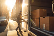 © MVProductions - Delivery man taking package out of back of truck in the morning sun, generative ai