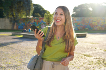 Poster - Latin young woman using mobile phone outdoor with colorful background on sunset