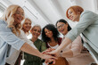 © gstockstudio - Low angle view of group of confident mature women stacking hands and smiling