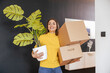 © ivanko80 - Happy young woman with  plant and boxes moving into new apartment