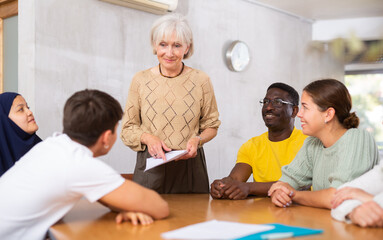 Elderly female manager holds round table meetings for employees of different nationalities