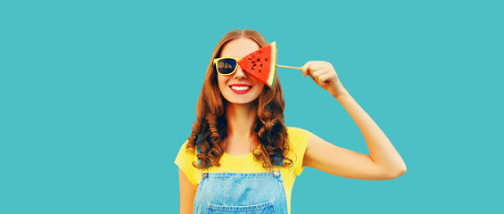 Wall Mural - Summer portrait of happy cheerful young woman with fresh juicy fruits, lollipop or ice cream shaped slice of watermelon on blue background