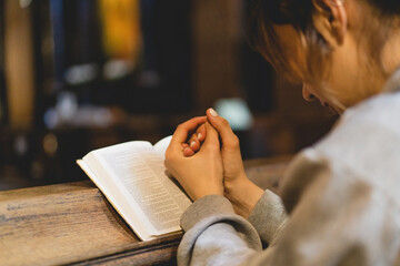 Christian woman reading bible in an ancient Catholic temple. Reading the Holy Bible in temple. Concept for faith, spirituality and religion. Peace, hope, dreams concept