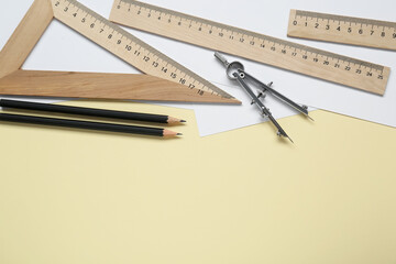 Wall Mural - Different rulers, pencils and compass on yellow background, flat lay. Space for text