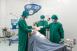 © chadchai - Group of surgeons and nurse in surgical green gown uniform performing surgical operation in operating room.