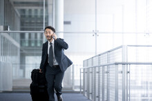 空港や駅でキャリーケース(スーツケース)を引きながら歩く40代ミドル・スーツ姿のアジア系の男性ビジネスマン 走る
