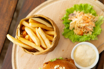 Wall Mural - Chicken burger and french fries on a wooden cutting board